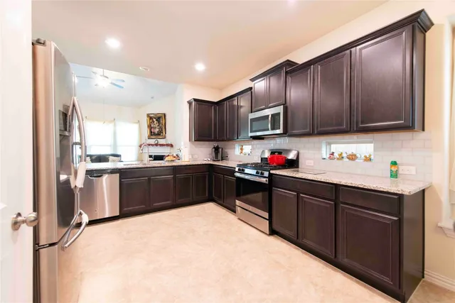 a kitchen with granite countertop wooden cabinets a stove top oven a sink and dishwasher