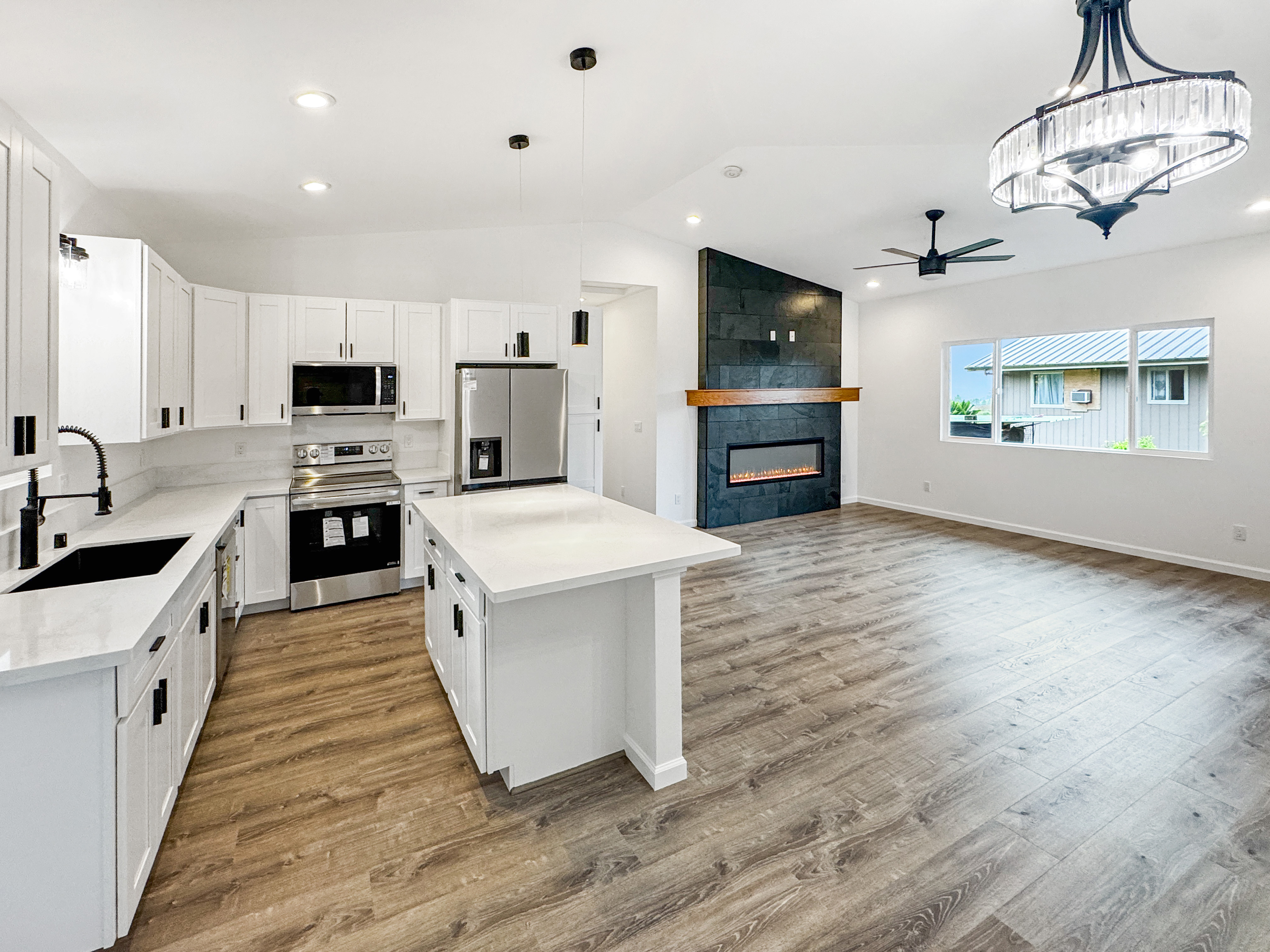 18-7846 Leonaka Road Mountain View, HI 96771 - Photo 3 of 13 a large kitchen with stainless steel appliances granite countertop a stove top oven a sink dishwasher and a refrigerator with wooden floor