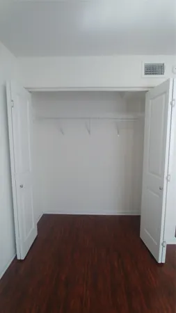 an empty room with wooden floor and cabinet