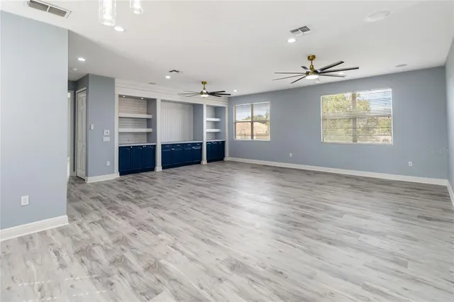 an empty room with ceiling fan and wooden floor