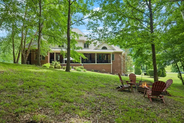 a view of the house with a big yard and large trees