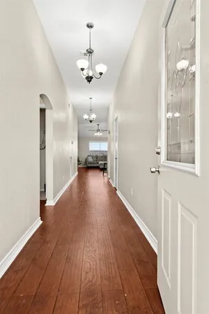 a view of a hallway with wooden floor and a kitchen