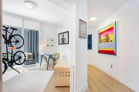 a view of a hallway with wooden floor and a bathroom
