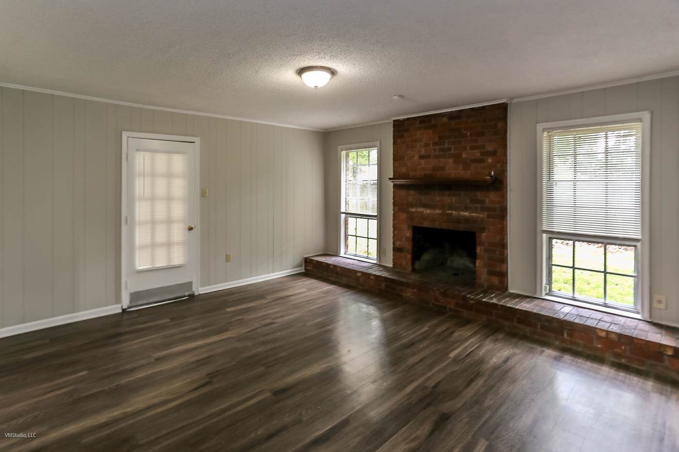 5217 Yale Road Memphis, TN 38134 - Photo 12 of 30 Unfurnished living room with dark wood-type flooring, a textured ceiling, a brick fireplace, and a healthy amount of sunlight