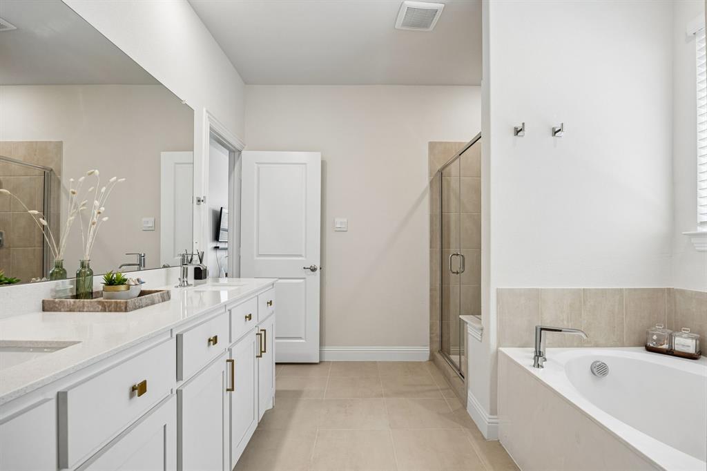 425 Breeds Hl Road Little Elm, TX 75068 - Photo 16 of 38 a spacious bathroom with double vanity a large mirror a bathtub and a shower