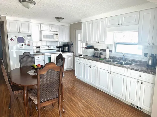 a kitchen with stainless steel appliances granite countertop a table chairs sink refrigerator and cabinets