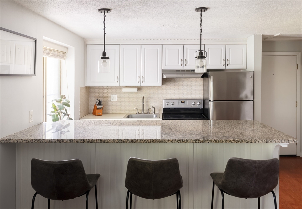 a kitchen with granite countertop a counter space chairs cabinets and appliances
