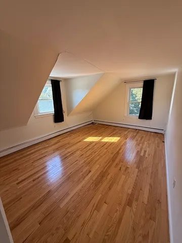 a view of an empty room with window and wooden floor