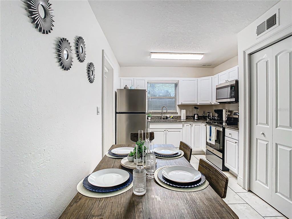 3025 Long Street Orlando, FL 32805 - Photo 8 of 24 a kitchen with stainless steel appliances granite countertop a refrigerator a stove a sink and a dining table with wooden floor