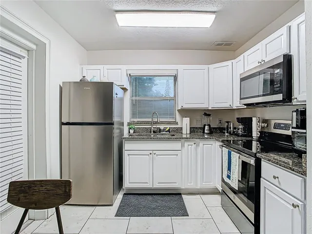 a kitchen with stainless steel appliances granite countertop a refrigerator stove a sink and a microwave