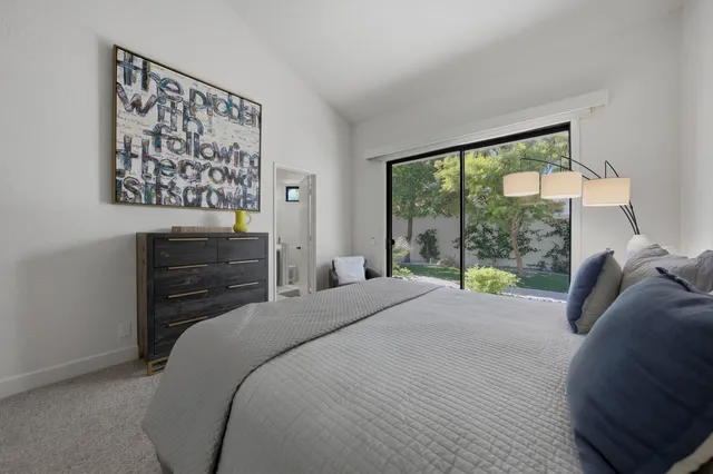 a bedroom with a bed and a dresser next to a window