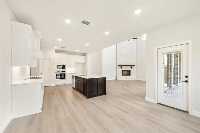 a large white kitchen with a large window and stainless steel appliances