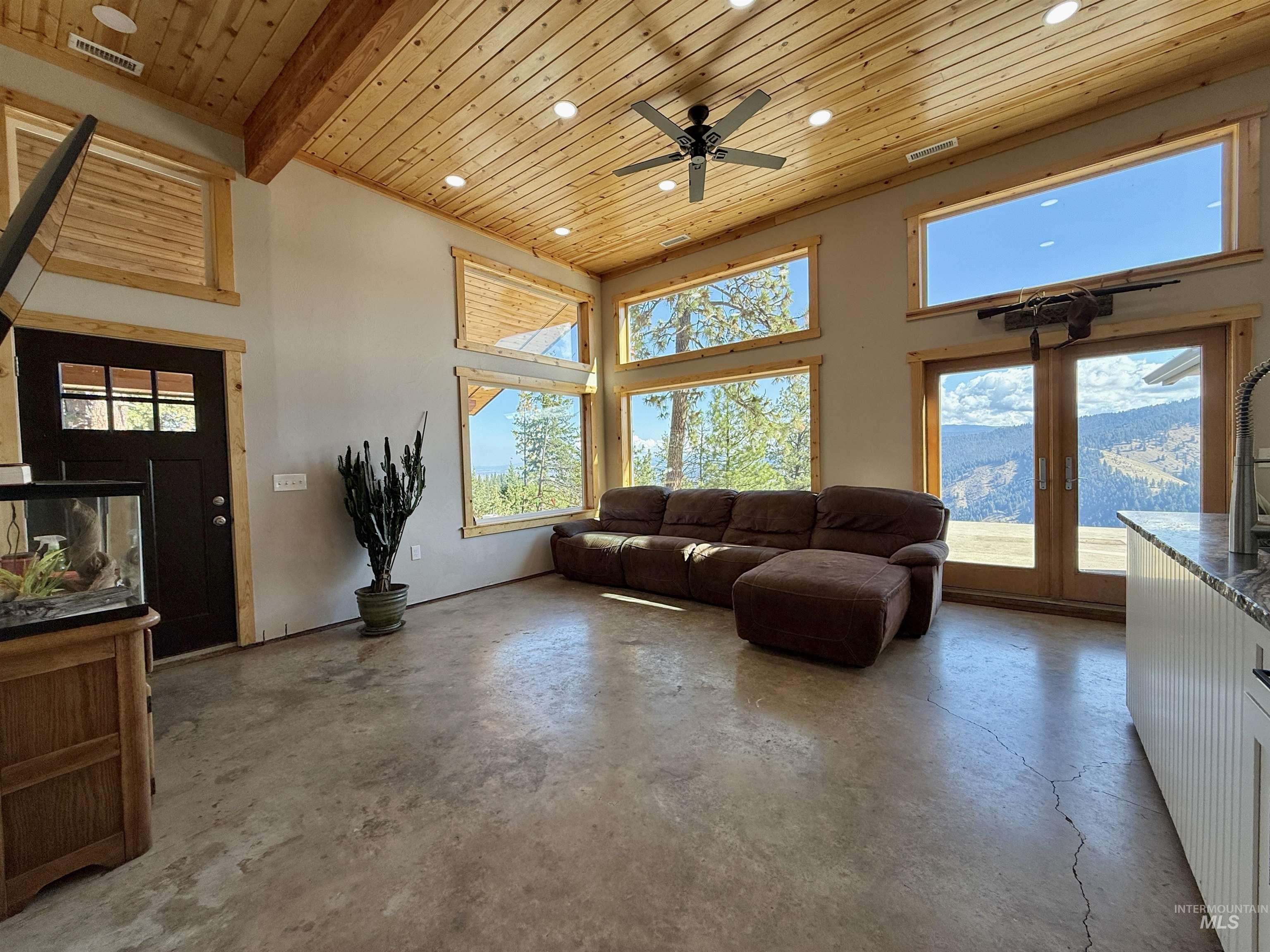 929 Mt Idaho Grade Road Grangeville, ID 83530 - Photo 6 of 47 Living room with wooden ceiling, unfinished concrete flooring, plenty of natural light, a high ceiling, and a ceiling fan
