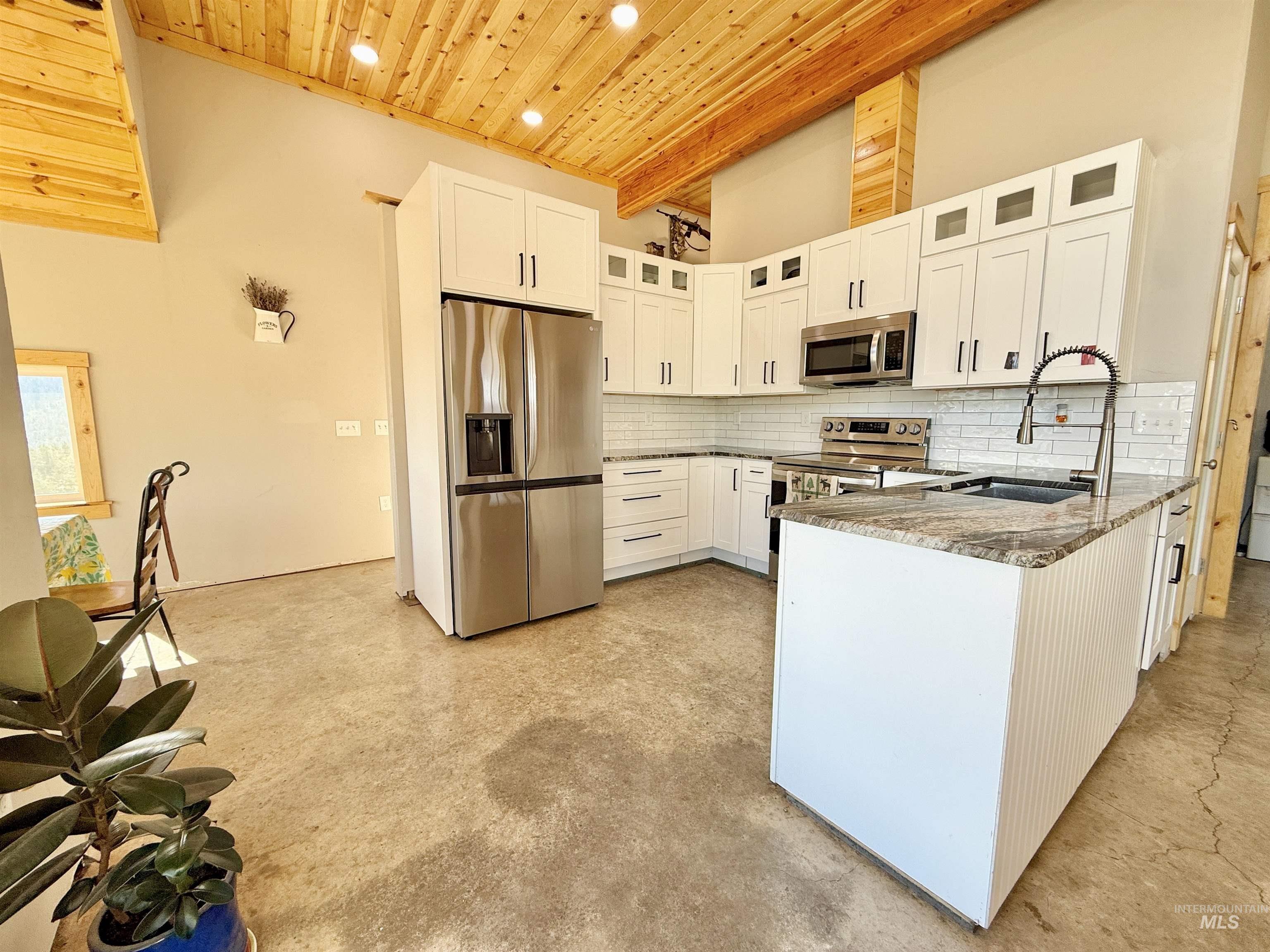 929 Mt Idaho Grade Road Grangeville, ID 83530 - Photo 9 of 47 Kitchen with a wood ceiling with exposed beams, dark stone counters, white cabinetry, glass insert cabinets, and stainless steel appliances