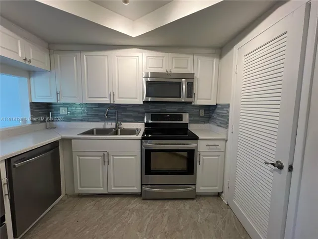 a kitchen with cabinets stainless steel appliances and sink