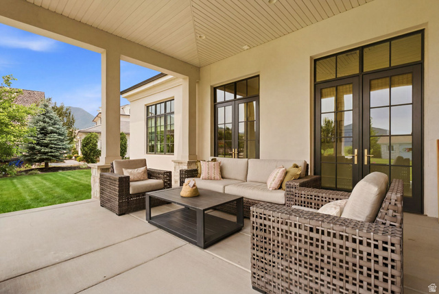 71 Farm Road Midway, UT 84049 - Photo 76 of 92 Covered concrete patio with overhead lighting, featuring multiple large grid-patterned glass doors, exterior stucco siding, and a manicured lawn