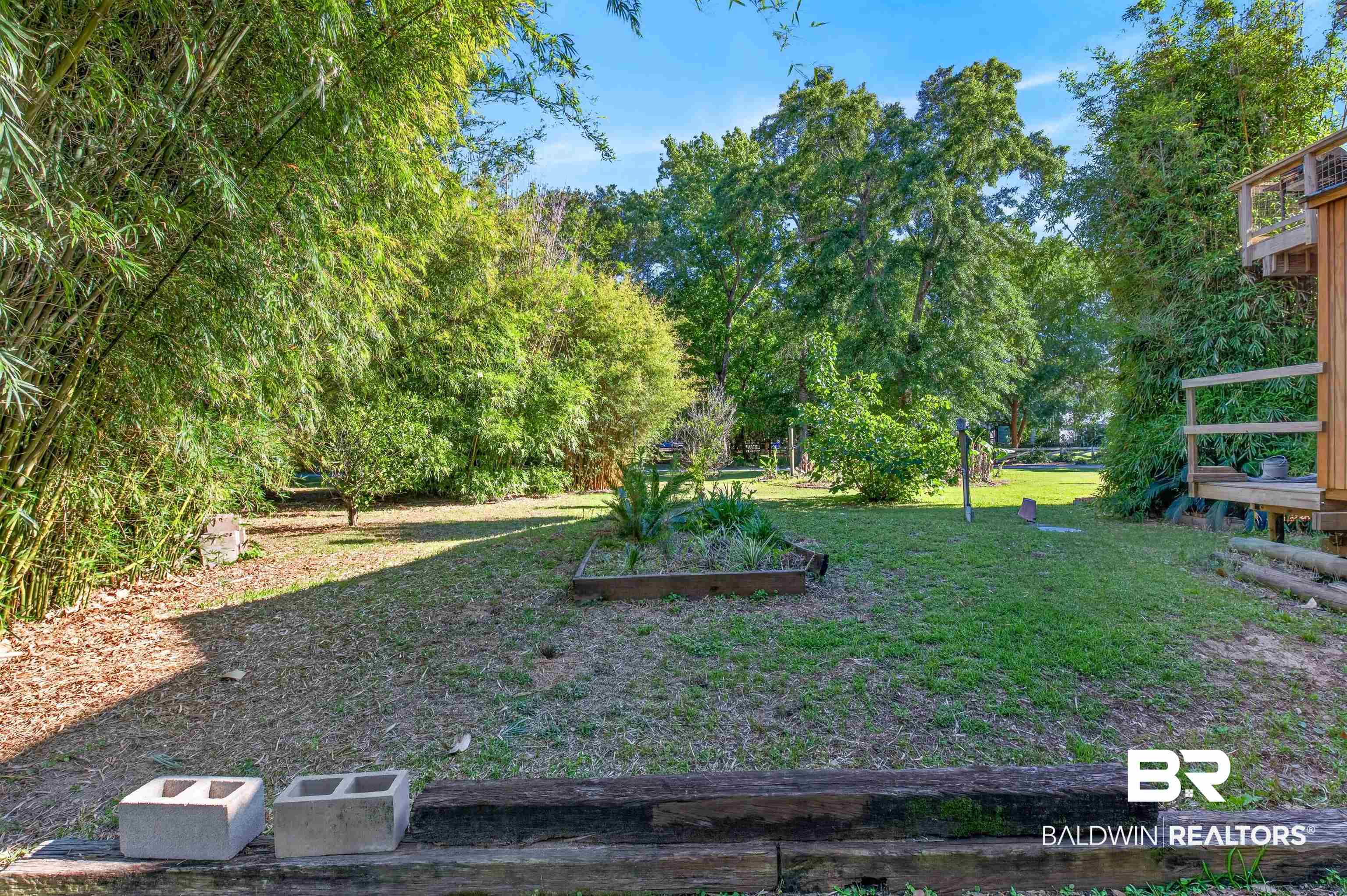 9624 North Bay Street Foley, AL 36535 - Photo 52 of 59 Expansive outdoor space featuring a grass lawn, mature trees, and bamboo landscaping