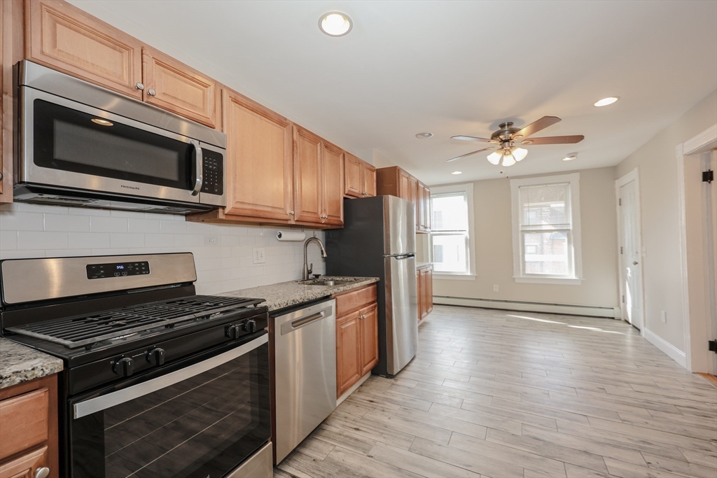 64 Bremen Street Boston, MA 02128 - Photo 5 of 42 a kitchen with stainless steel appliances granite countertop a stove top oven microwave and cabinets