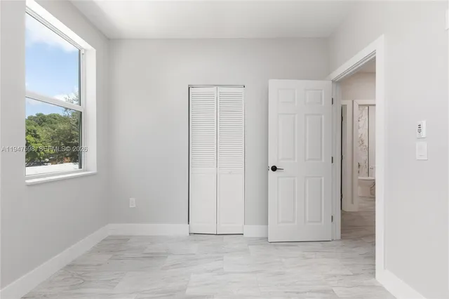 a view of an empty room with window and closet area
