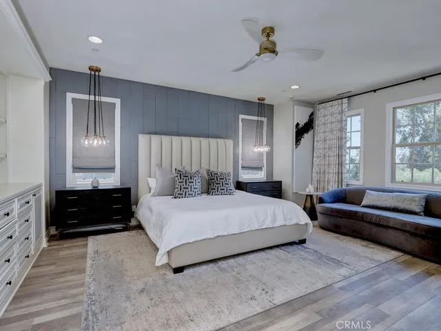 a living room with couches a mirror and a large window with wooden floor
