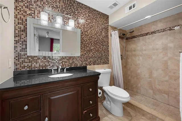 a bathroom with a granite countertop toilet and a sink