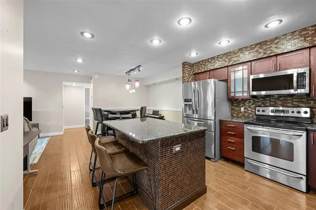 a kitchen with stainless steel appliances granite countertop a refrigerator a stove and a sink
