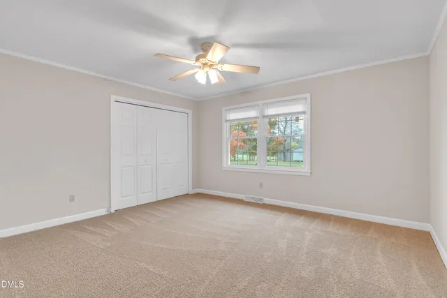 an empty room with windows and fan