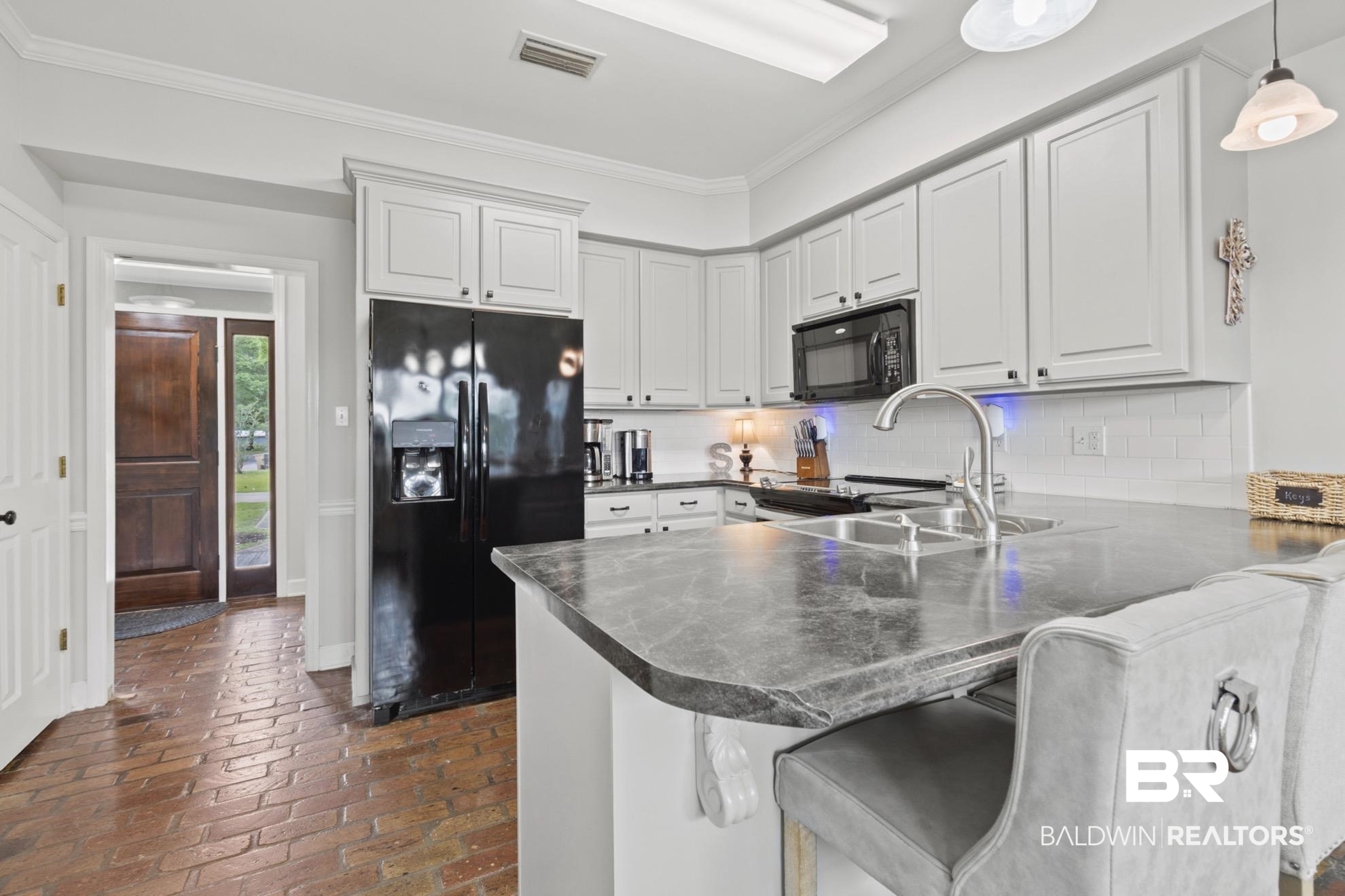 12171 Marguerite Drive Coden, AL 36523 - Photo 8 of 44 Kitchen featuring light-toned cabinetry, a dark countertop island with an integrated sink, and an undermount microwave