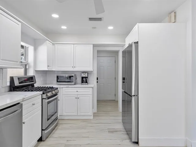 a kitchen with a refrigerator a stove top oven and white cabinets