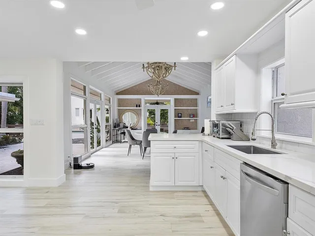 a kitchen with stainless steel appliances granite countertop a sink dishwasher and white cabinets with wooden floor