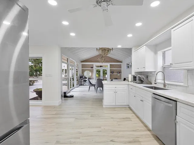 a view of a kitchen with kitchen island a counter top space a sink stainless steel appliances and cabinets
