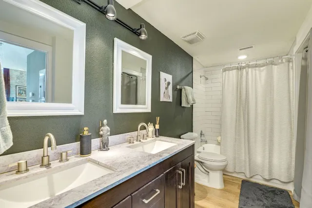 a bathroom with a granite countertop sink and a mirror with toilet