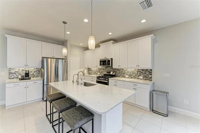 a kitchen with stainless steel appliances a sink a stove a refrigerator and a oven