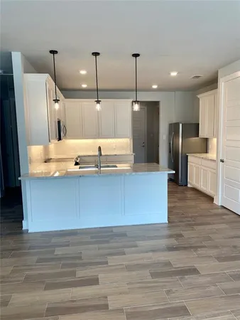 a kitchen with stainless steel appliances granite countertop a sink a stove top oven a counter space and wooden floor