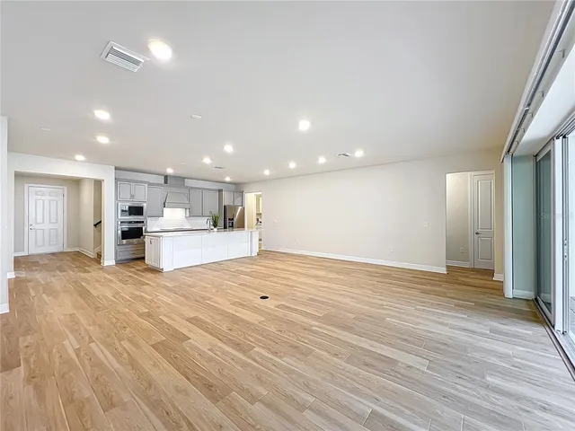 a large kitchen with kitchen island a sink dishwasher stove and white cabinets with wooden floor