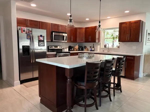a kitchen with stainless steel appliances granite countertop a table chairs sink refrigerator and microwave