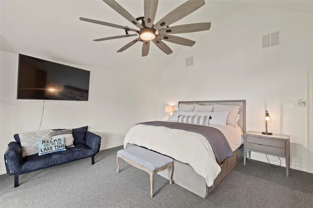 a bedroom with a bed a couch and a flat screen tv