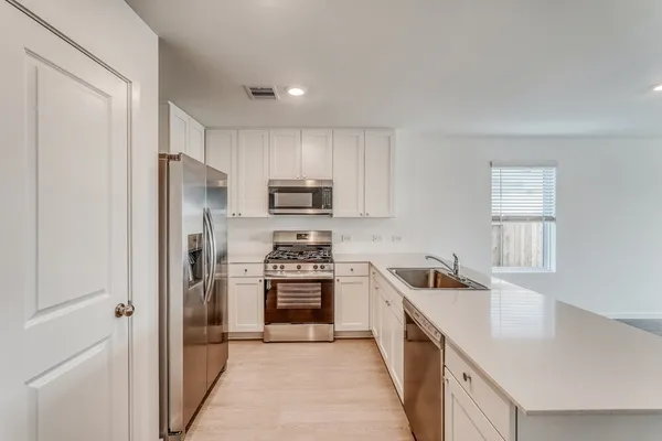 a kitchen with a refrigerator a microwave a sink and cabinets
