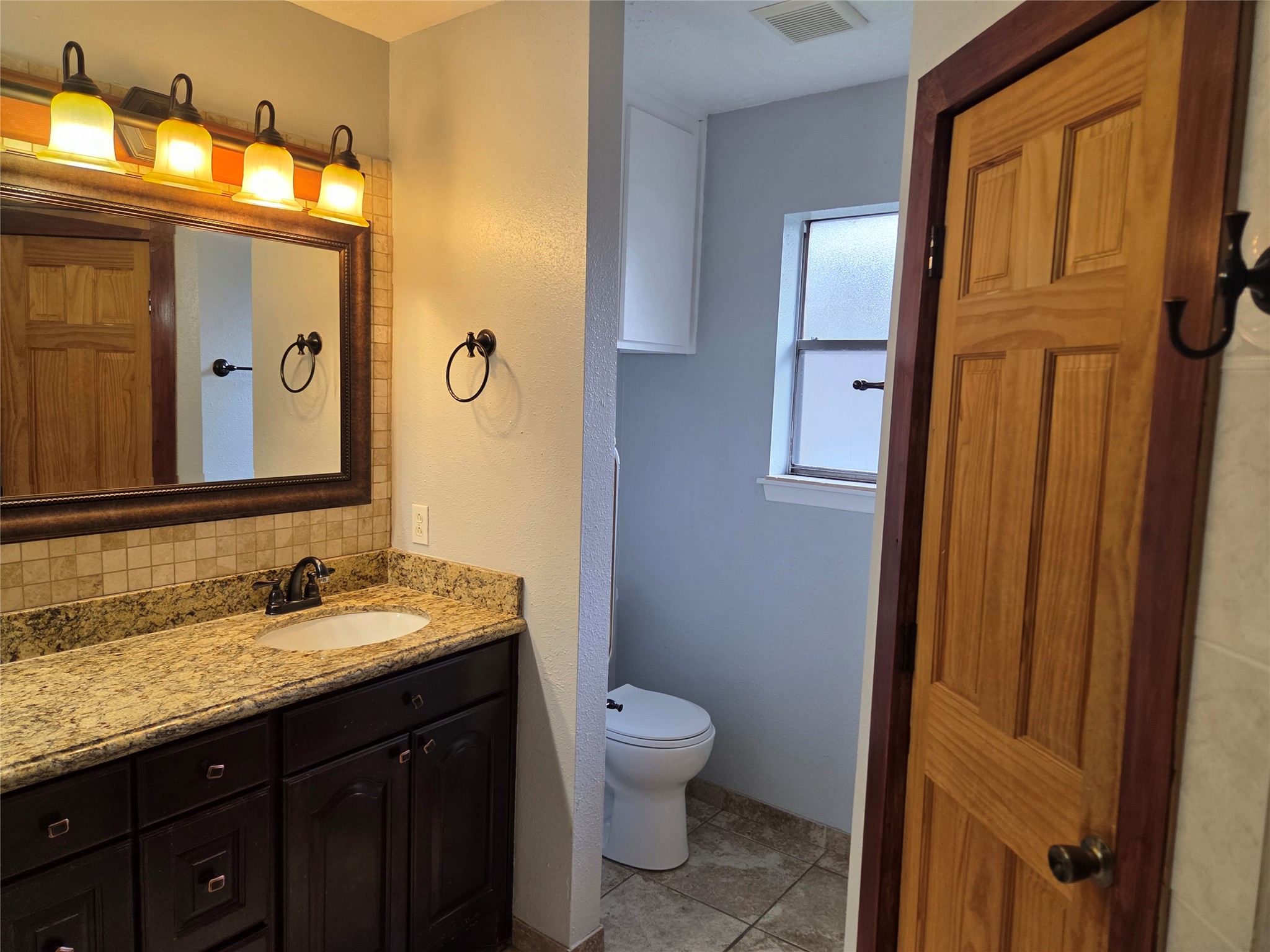 15415 Beechnut Street Houston, TX 77083 - Photo 16 of 28 a bathroom with a granite countertop toilet a sink and a mirror