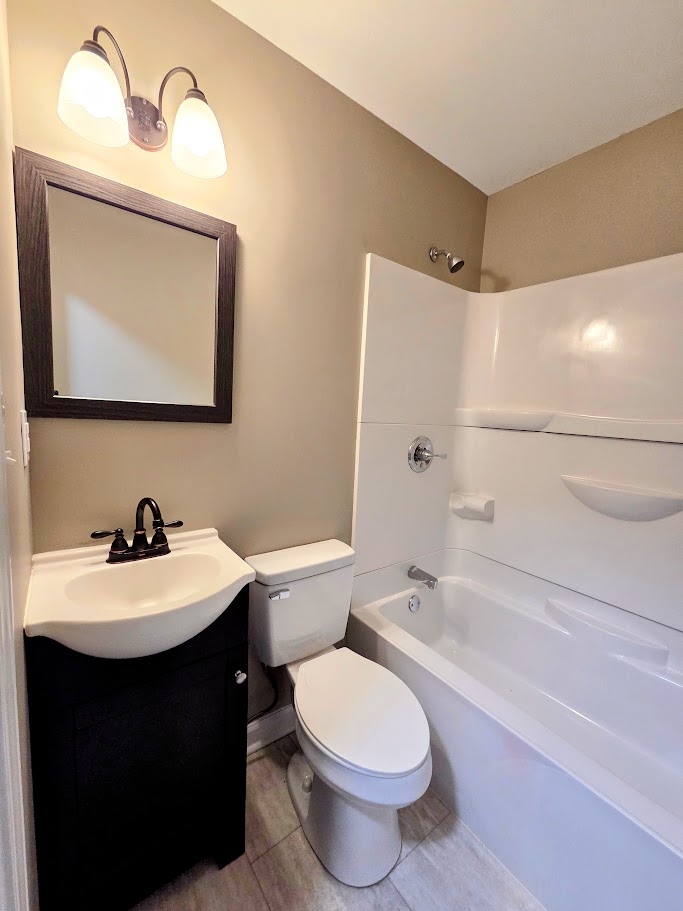 509 Elrod Road Piedmont, SC 29673 - Photo 19 of 28 A well-lit, compact bathroom showcases a clean white tub and shower combination alongside a modern vanity with dark cabinetry.