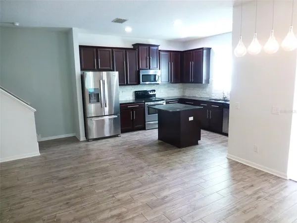 a kitchen with stainless steel appliances granite countertop a refrigerator stove a sink and dishwasher with wooden floor