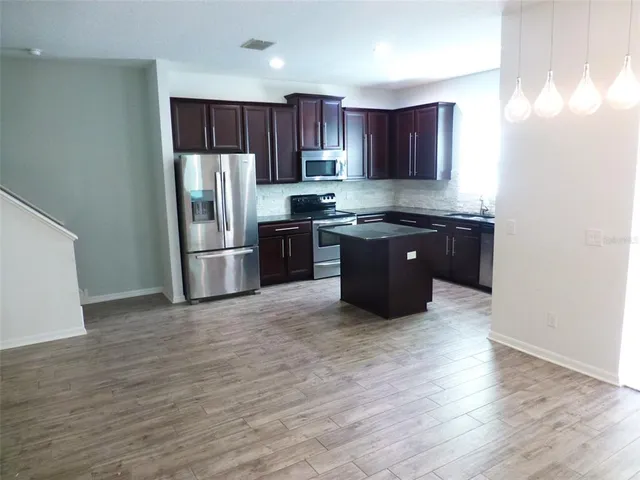 a kitchen with stainless steel appliances granite countertop a refrigerator stove a sink and dishwasher with wooden floor