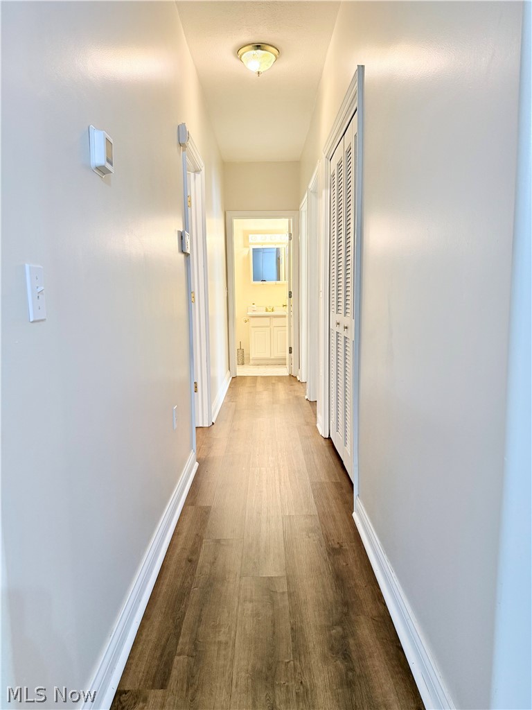 603 South Raccoon Road, Unit 1 Austintown, OH 44515 - Photo 10 of 22 Hallway featuring wood-finish flooring, white baseboards, and a flush-mount ceiling light