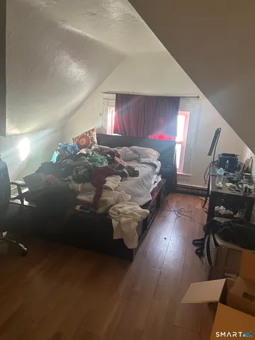 a spacious bedroom with a bed and wooden floor