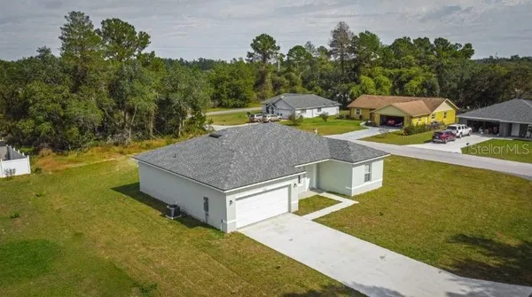 a aerial view of a house with swimming pool and trees in the background