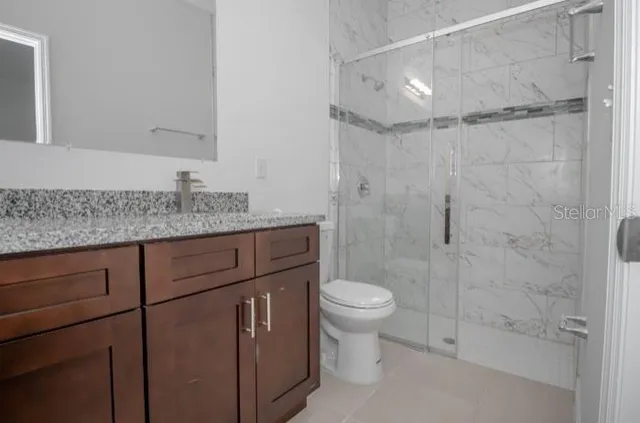 a bathroom with a granite countertop sink toilet a mirror and shower