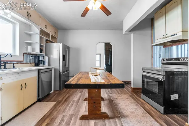 a kitchen with stainless steel appliances granite countertop a refrigerator a sink dishwasher a stove and white countertops with wooden floor