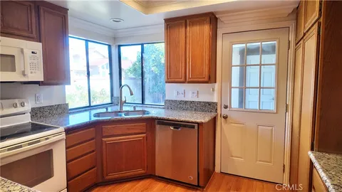 a kitchen with stainless steel appliances granite countertop wooden cabinets a sink and a large window
