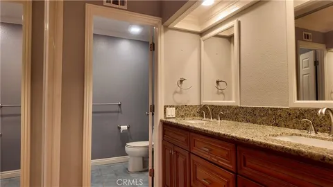 a bathroom with a granite countertop sink a toilet and a large mirror