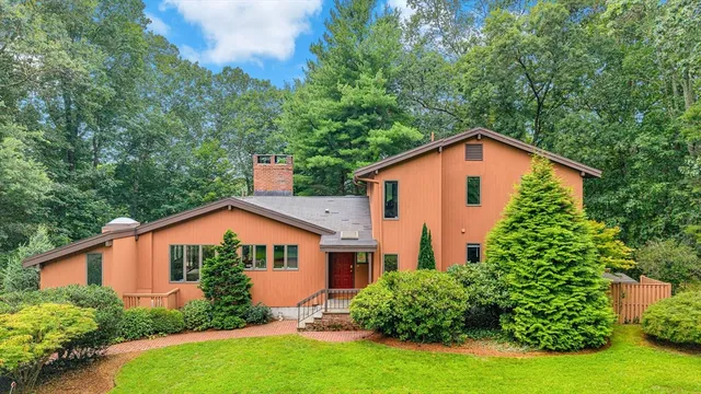 a view of a yard in front of a house with plants and large trees